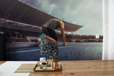 Fototapeta Sprinter opierając stopy na bloku startowym na bieżni