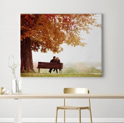 Obraz na płótnie Młoda para całuje na ławce pod ogromnym kasztanem