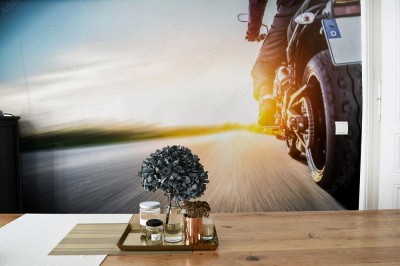 Fototapeta Motocykl jedzie po otwartej wiejskiej drodze o zachódzie słońca