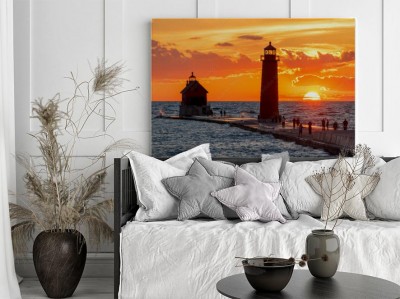 Obraz na płótnie latarnia morska o zachodzie słońca z sylwetkami ludzi